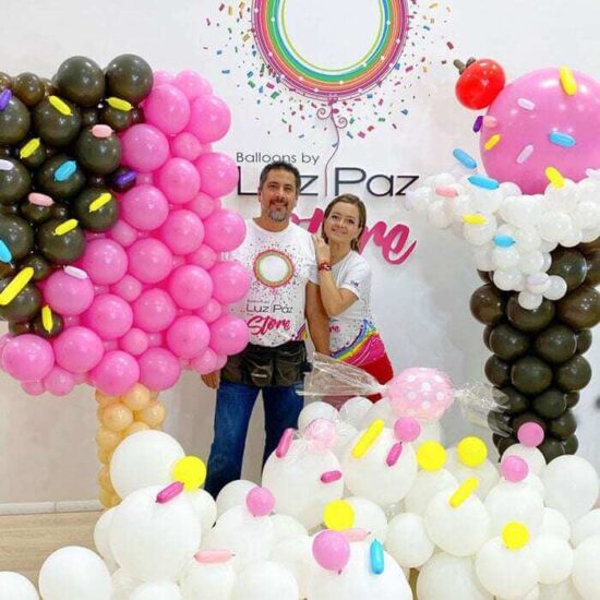 Luz Paz y Omar Bucio junto a Escultura de helados con globos.