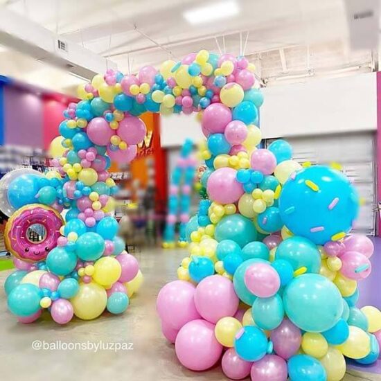 Arco de globos con técnica orgánica y temática de dulces coloridos.