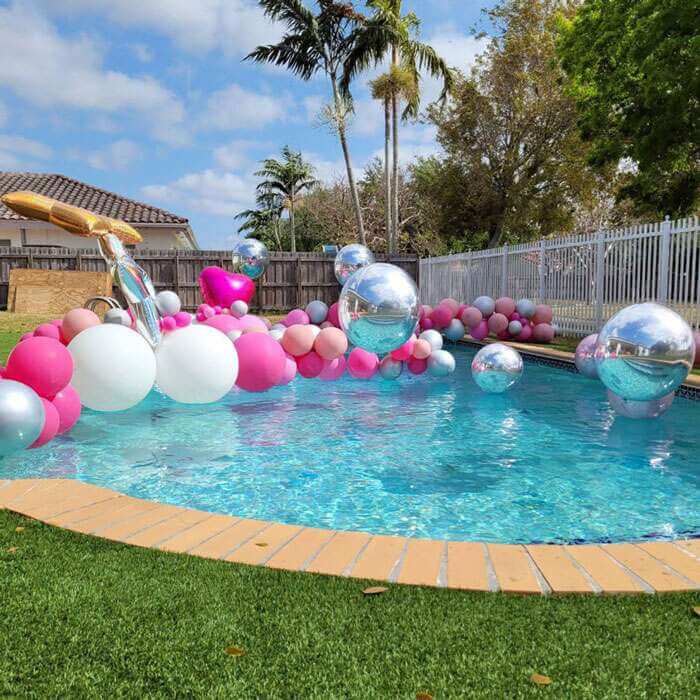 Piscina al aire libre recubierta por arcos con globos flotantes y globos flotantes gigantes.