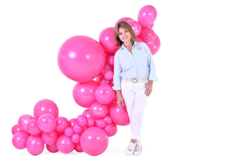 Luz Paz junto a guirnalda con globos en tonos rosa.